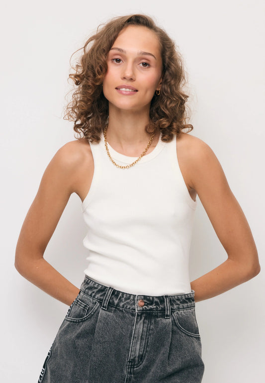 Modelka w białym prążkowanym topie ALEXIN i logowaną taśmą na plecach.