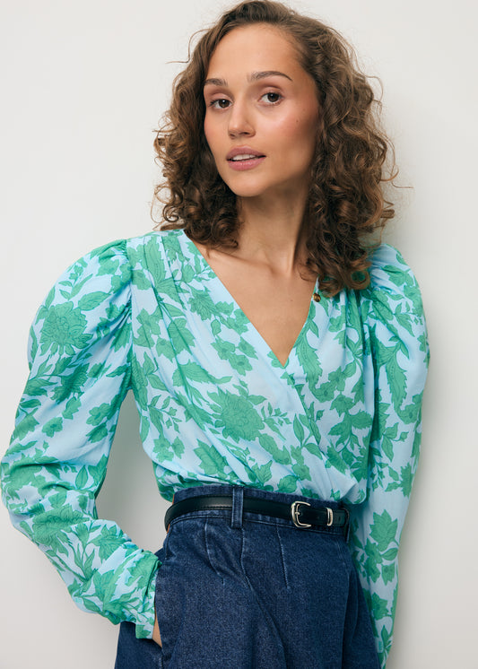 Zbliżenie na modelkę ubraną w niebieskie body w autorski print ALIBA oraz mini spódniczkę z jeansu BREDA.