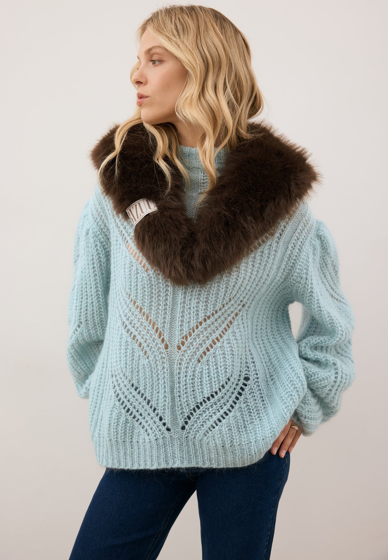 Modelka patrząca w bok ubrana w sweter ROSSO oraz futrzany szalik FLOOFU.