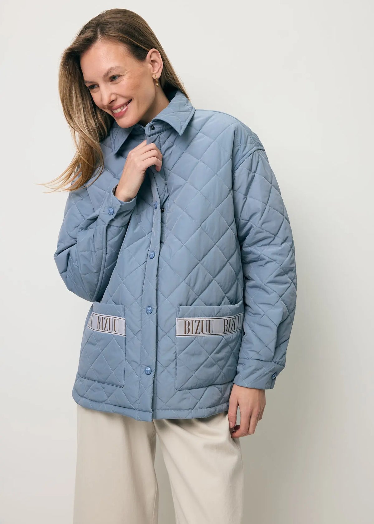 Uśmiechnięta modelka ubrana w błękitną kurtkę z logowaną taśmą MARIN.