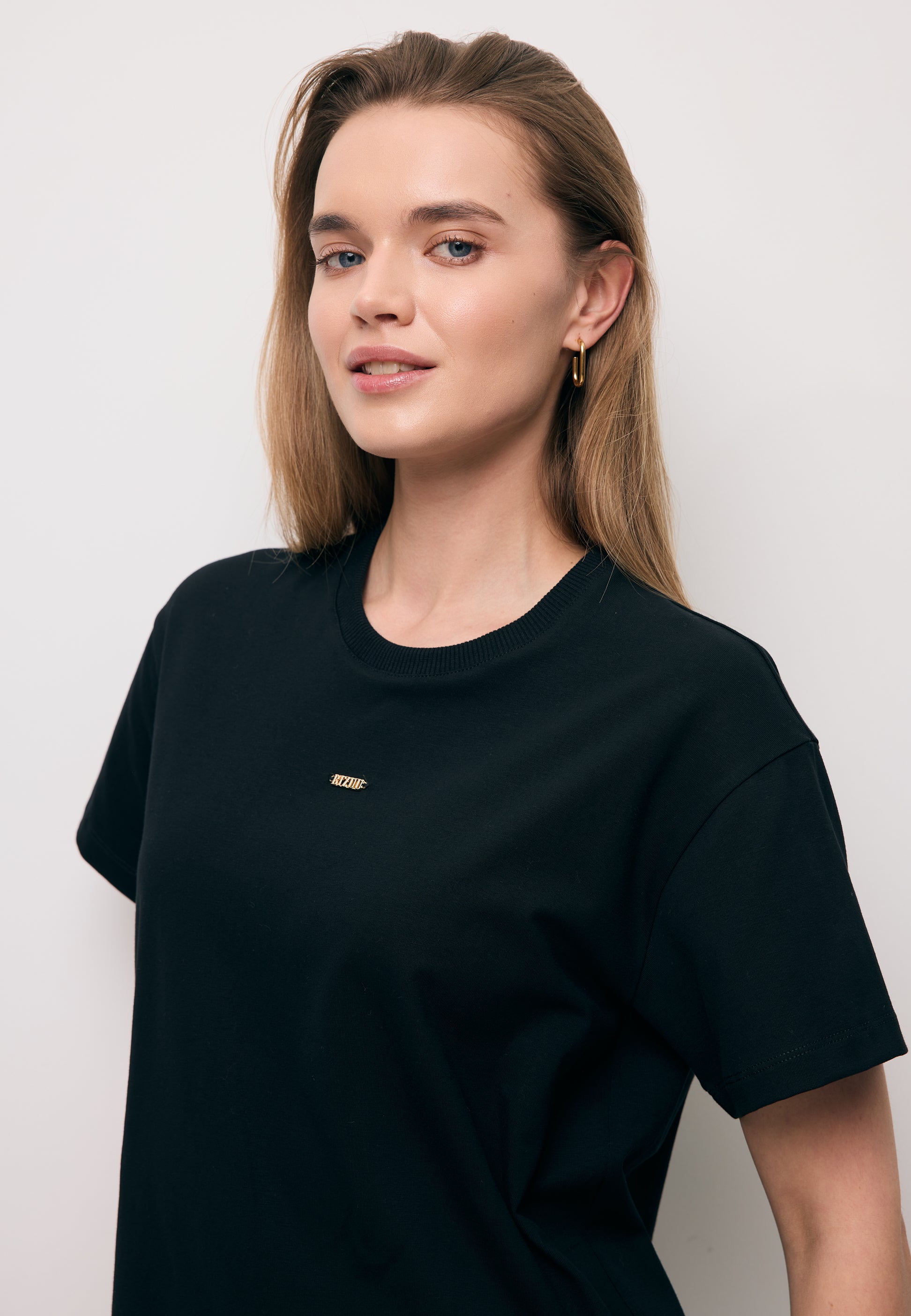 Zbliżenie na modelkę w czarnym T-shircie TISHAL z logo na przodzie.