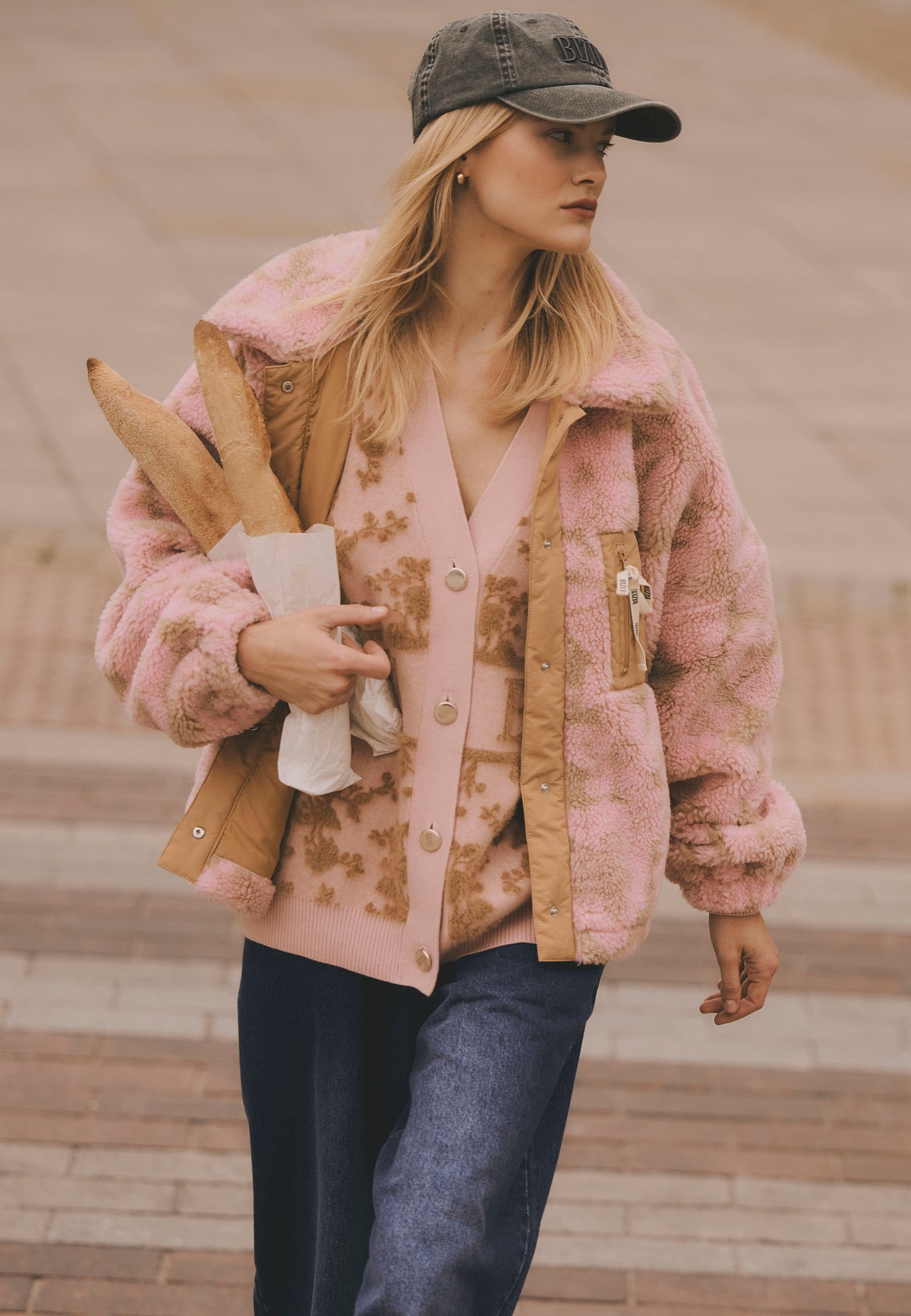 Modelka przechodząca przez pasy w polarze TEDDY w kwiecisty wzór, kardigan LANZAR i granatowe jeansy LEYA.